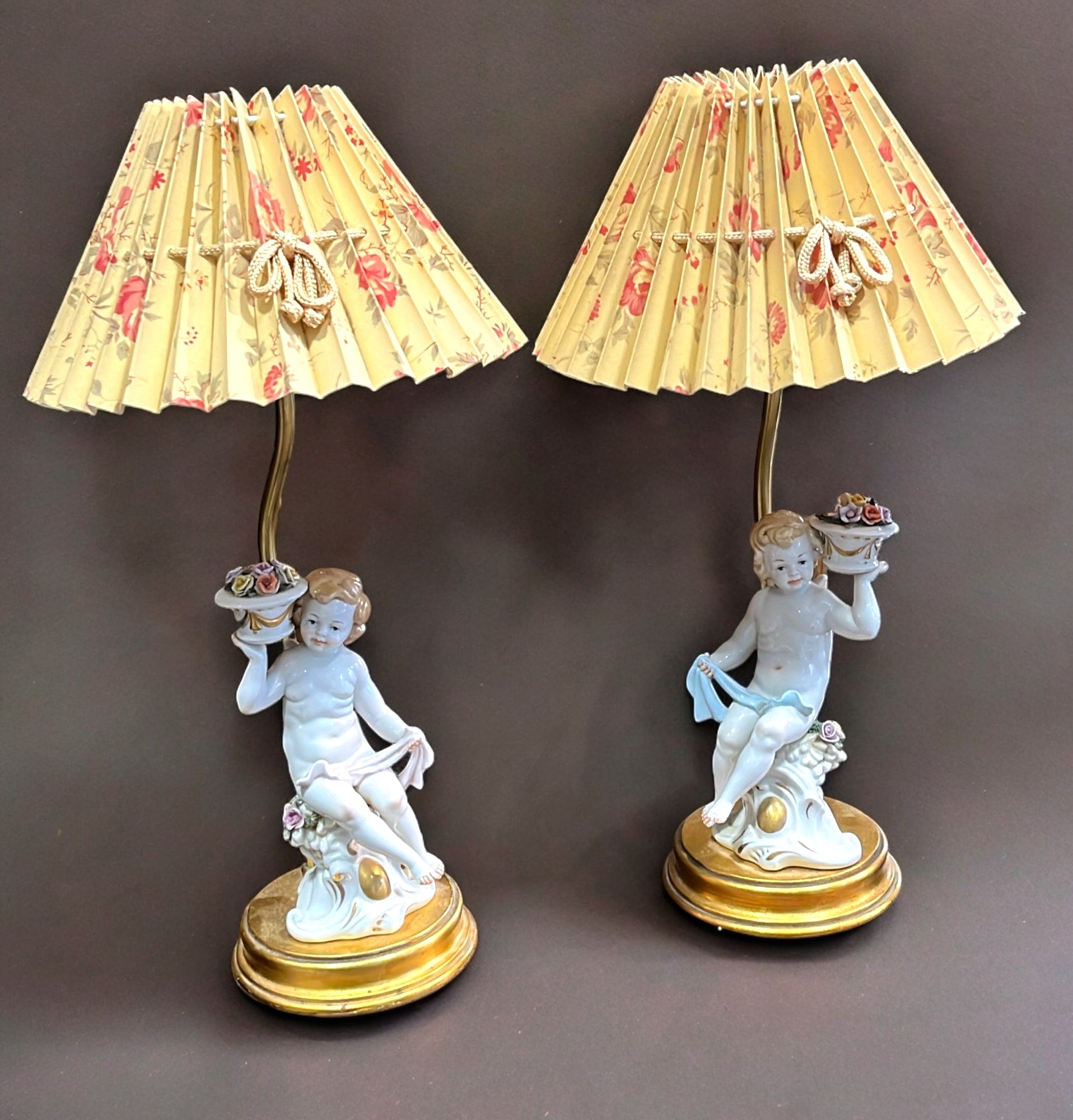 Pareja de lámparas de noche con querubines de porcelana y pantallas plisadas con diseño floral, ideales para decoración vintage.