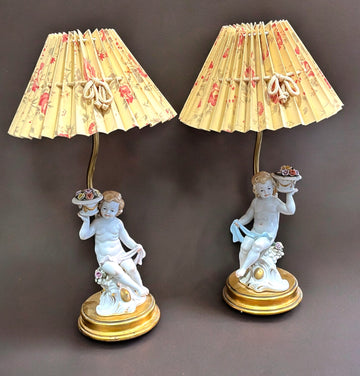 Pareja de lámparas de noche con querubines de porcelana y pantallas plisadas con diseño floral, ideales para decoración vintage.
