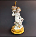 Detalle de querubín de porcelana con base dorada, parte de una lámpara de noche decorativa de estilo vintage.