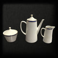 Cafetera, azucarera y jarra del Juego de Café Epiag de Porcelana Fina con detalles en azul, dorado y blanco, ideal para decoración refinada.