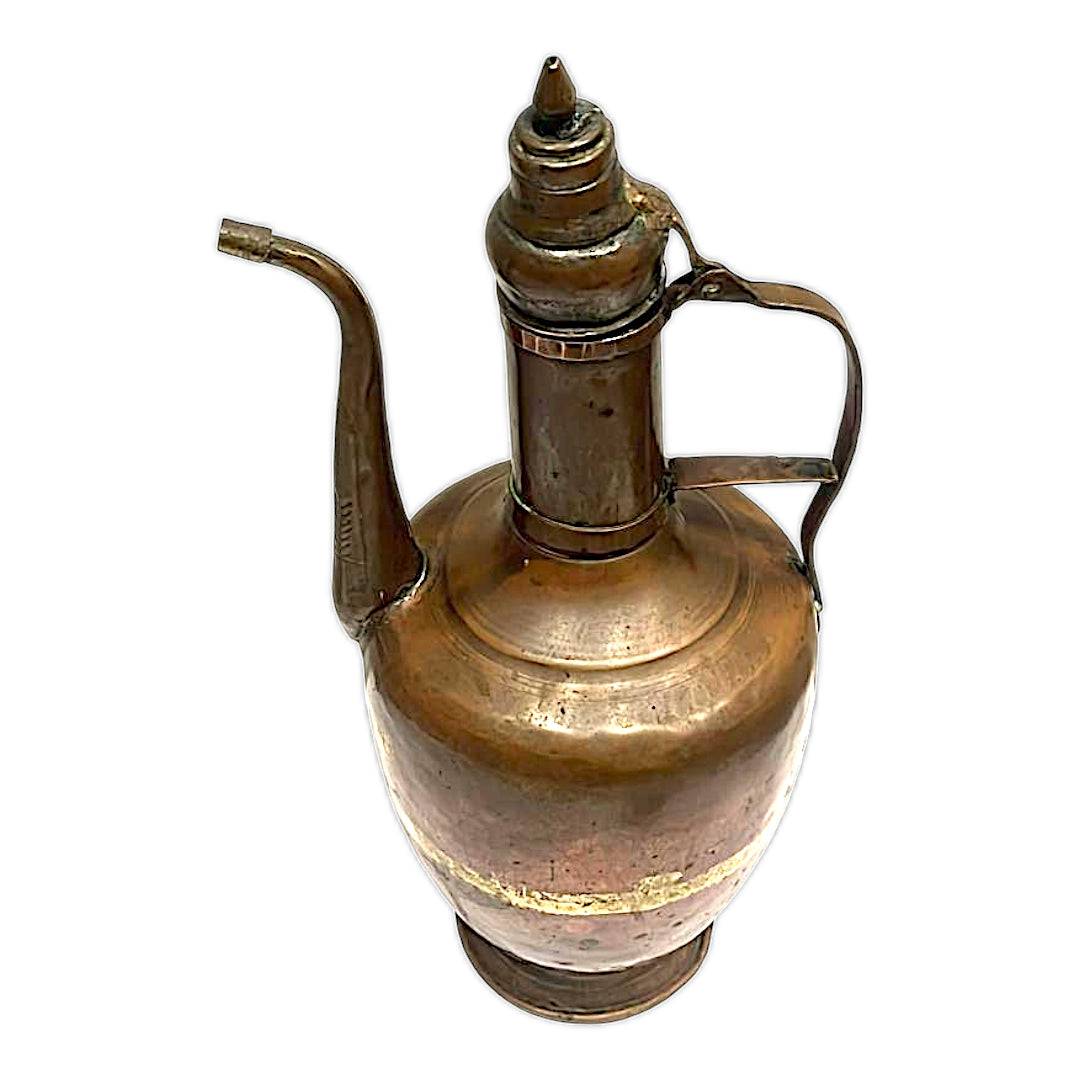 Vista superior de tetera de cobre antigua con pico largo y tapa decorativa, pieza única para coleccionistas y amantes del estilo retro en decoración.