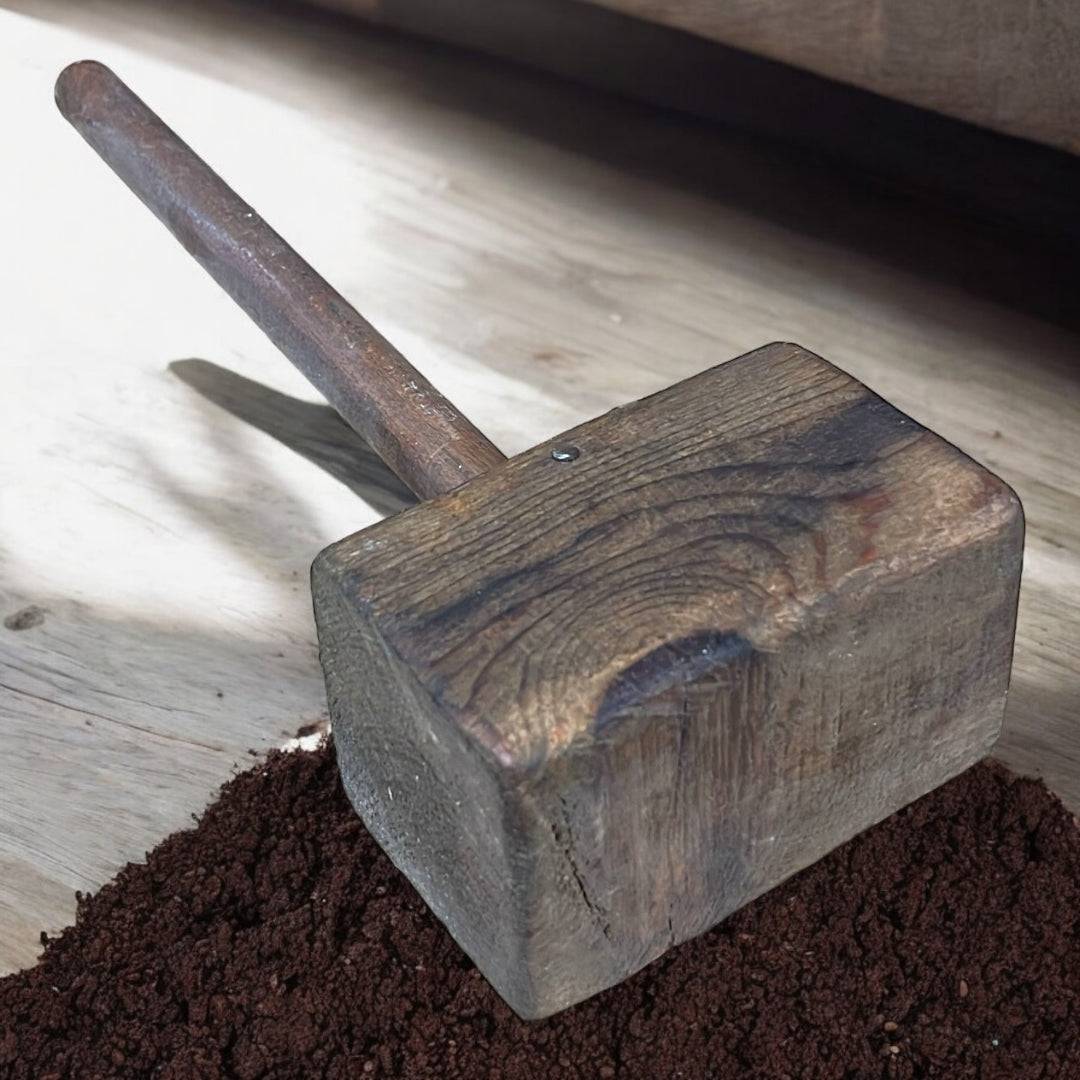 Mazo de madera antiguo con acabado rústico sobre superficie de madera clara, pieza única decorativa para ambientes vintage e industriales.