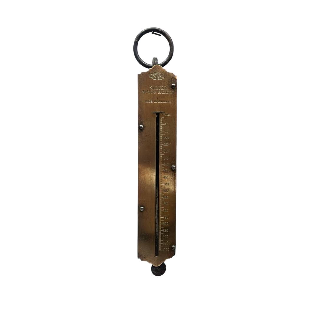 Balanza antigua de colgar en metal con escala grabada, pieza única y exclusiva para coleccionistas de decoración vintage.