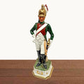 Figura de porcelana de soldado dragón napoleónico multicolor, con postura firme y detalles dorados, ideal para decoración histórica.