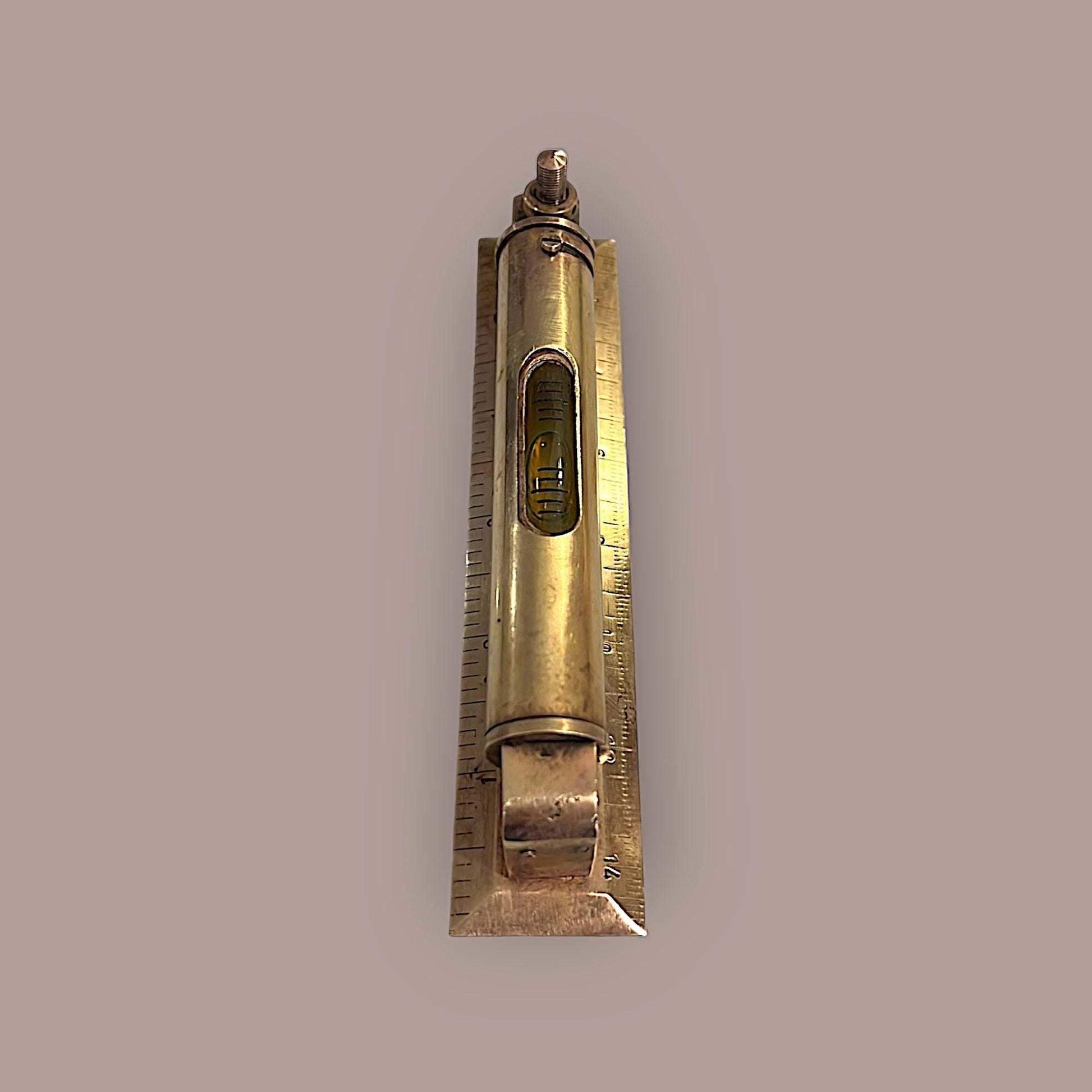 Nivel metálico de precisión con burbuja visible y base milimetrada de 14 cm, estilo antiguo para proyectos decorativos en hogar y jardín.
