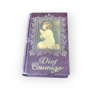 Portada del libro 'Dios Conmigo' con encuadernación púrpura y diseño religioso, parte de los libros de oraciones religiosas antiguos únicos y coleccionables.