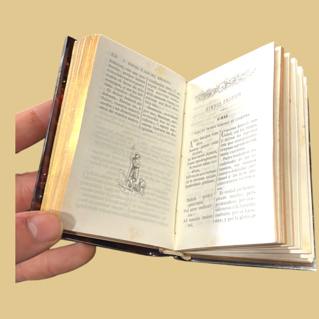 Interior del libro misal antiguo con páginas ilustradas y textos religiosos. Pieza única con encuadernación de lujo y bordes dorados.