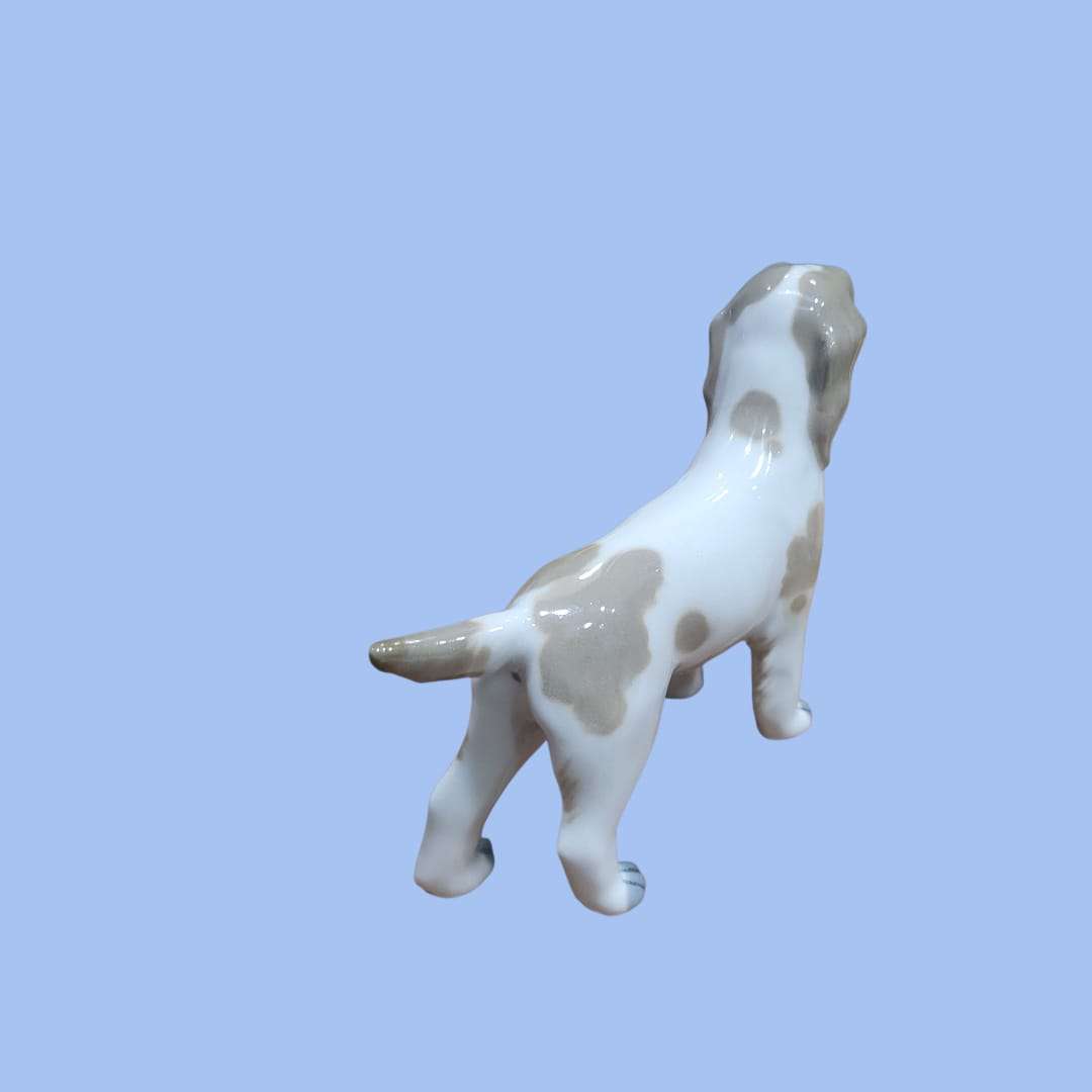 Perro de porcelana Lladró, pieza decorativa exclusiva con acabado brillante y detalles artesanales en tonos beige y blanco. Ideal para decoración de interiores.