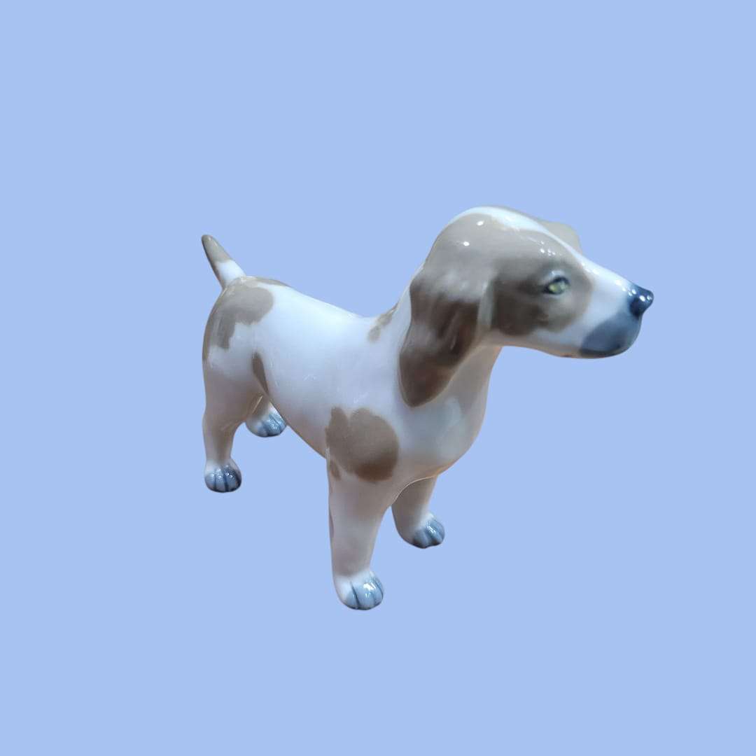 Figura decorativa de perro de porcelana Lladró, pieza exclusiva con expresión detallada y patas esmaltadas. Complemento elegante para el hogar.