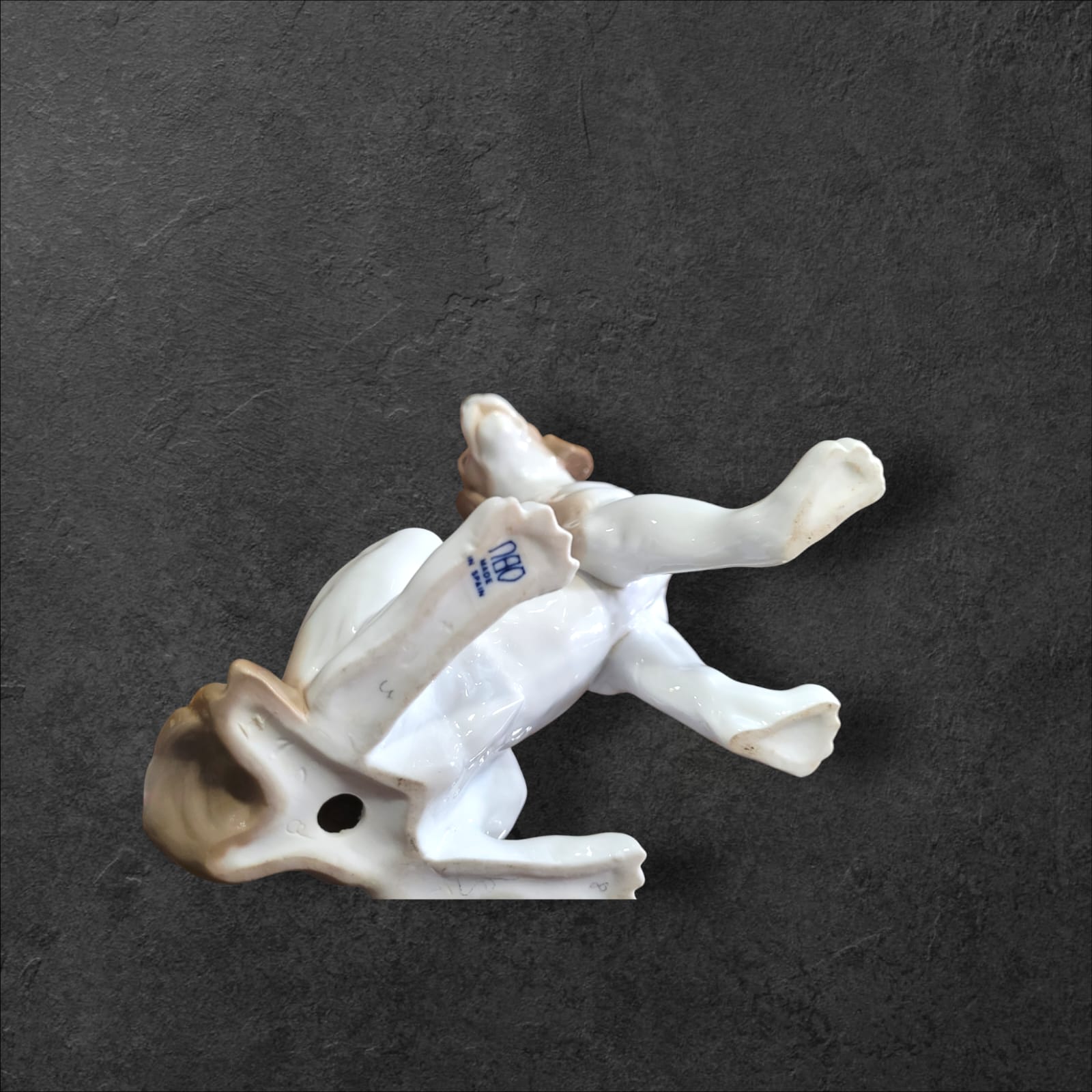 Base de la figura de perro en porcelana Nao Lladró, mostrando detalles del acabado artesanal y el sello de autenticidad.