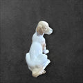 Vista lateral de la figura de perro en porcelana Nao Lladró, resaltando su acabado bicolor y pose tierna.