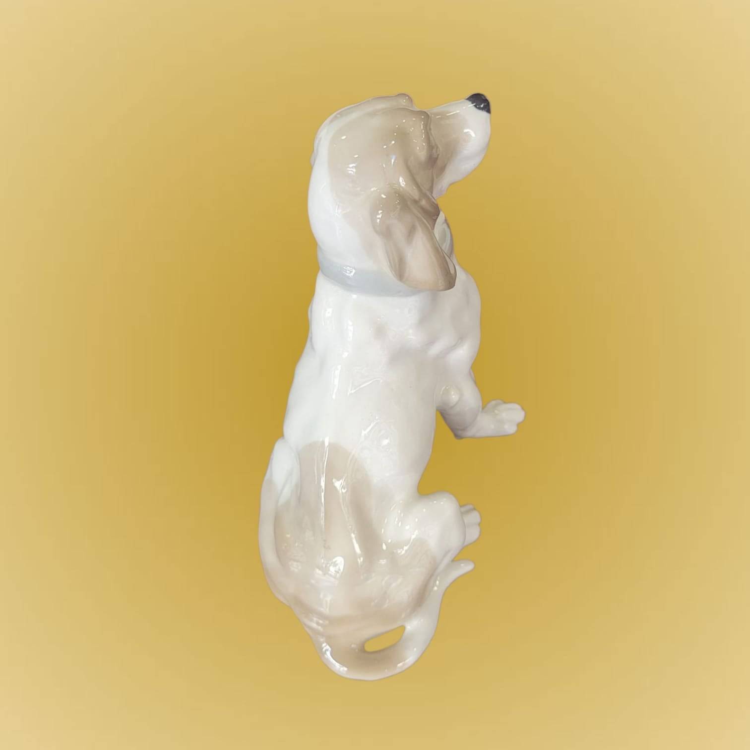 Vista superior de figura de porcelana Perro Cocker - Figura Elegante, mostrando textura detallada y acabado artesanal en tonos beige y blanco.