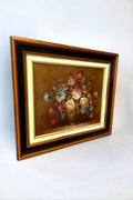 Pintura al óleo de Juan Lara con flores detalladas y marco clásico en tonos dorado, negro y marrón. Ideal para embellecer espacios con arte refinado.