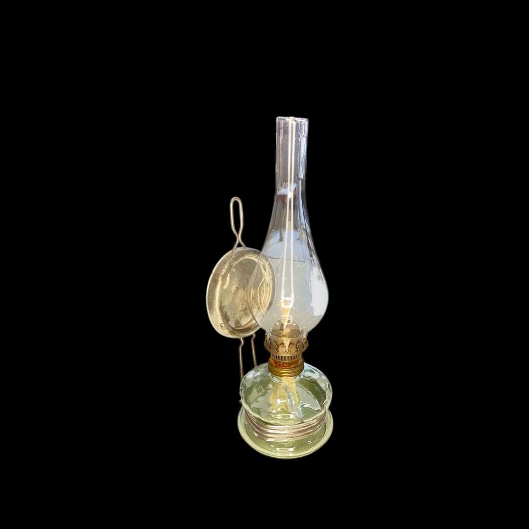 Quinqué de cristal antiguo visto de frente con soporte metálico.