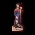 Figura frontal de San Roque en terracota esmaltada con perro, bastón y base con inscripción. Decoración artesanal disponible en Cositas Antiguas.