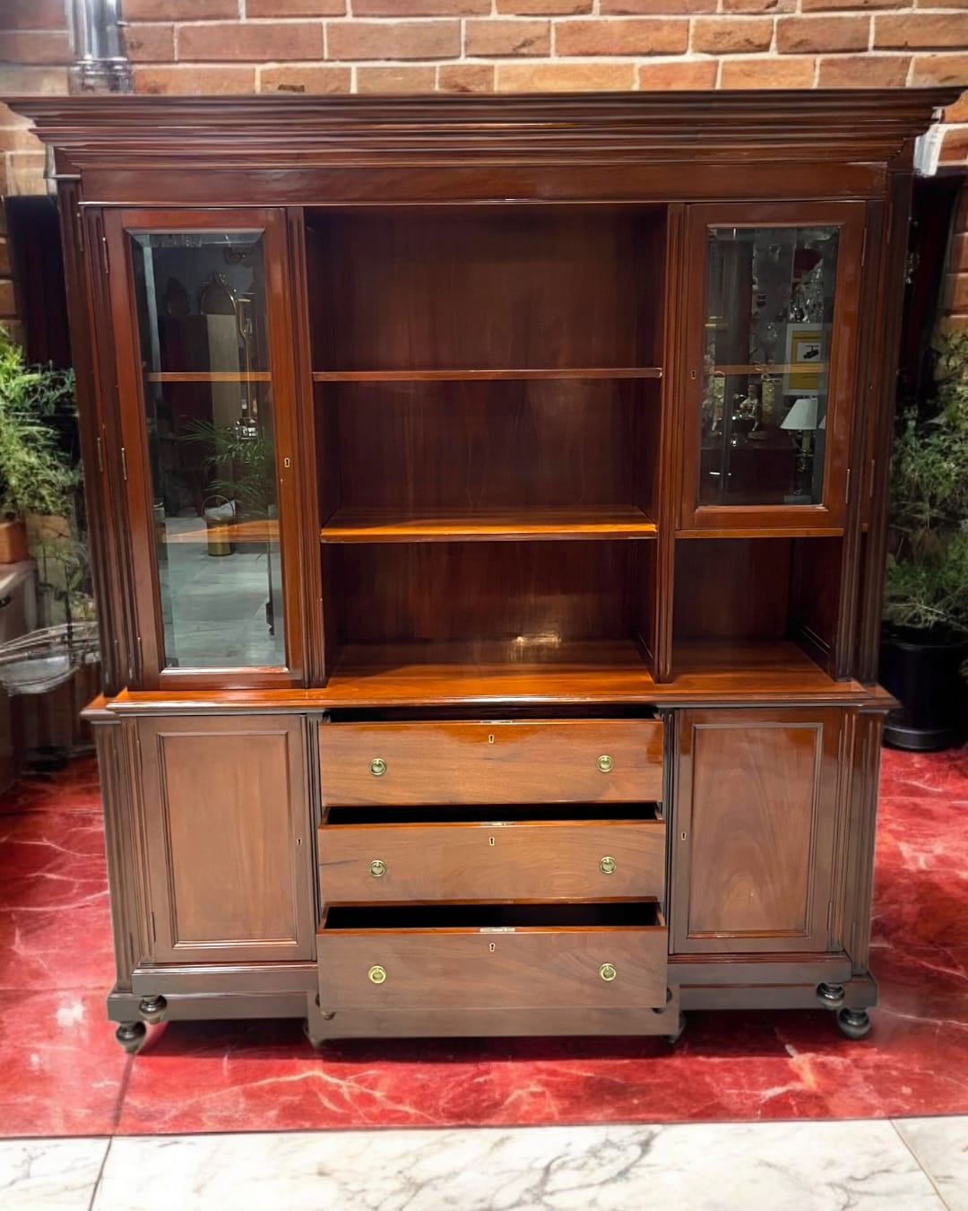 Elegante librería-aparador de caoba maciza con cajones abiertos y vitrinas laterales. Un mueble clásico ideal para decoración y organización.