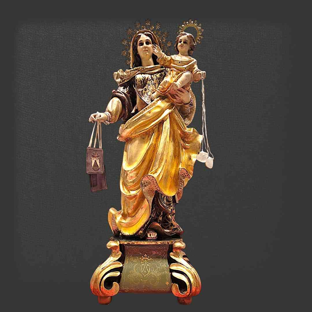 Figura frontal de la Virgen del Carmen de Olot con Niño Jesús, destacando ojos de cristal, acabados dorados y base decorativa.