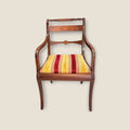 Sillón individual de caoba con taracea y brazos curvos, asiento tapizado a rayas cálidas. Perfecto para despacho o rincón decorativo clásico.