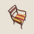 Vista en ángulo de sillón de caoba con taracea, brazos curvos y asiento rayado multicolor. Pieza decorativa para ambientes tradicionales.