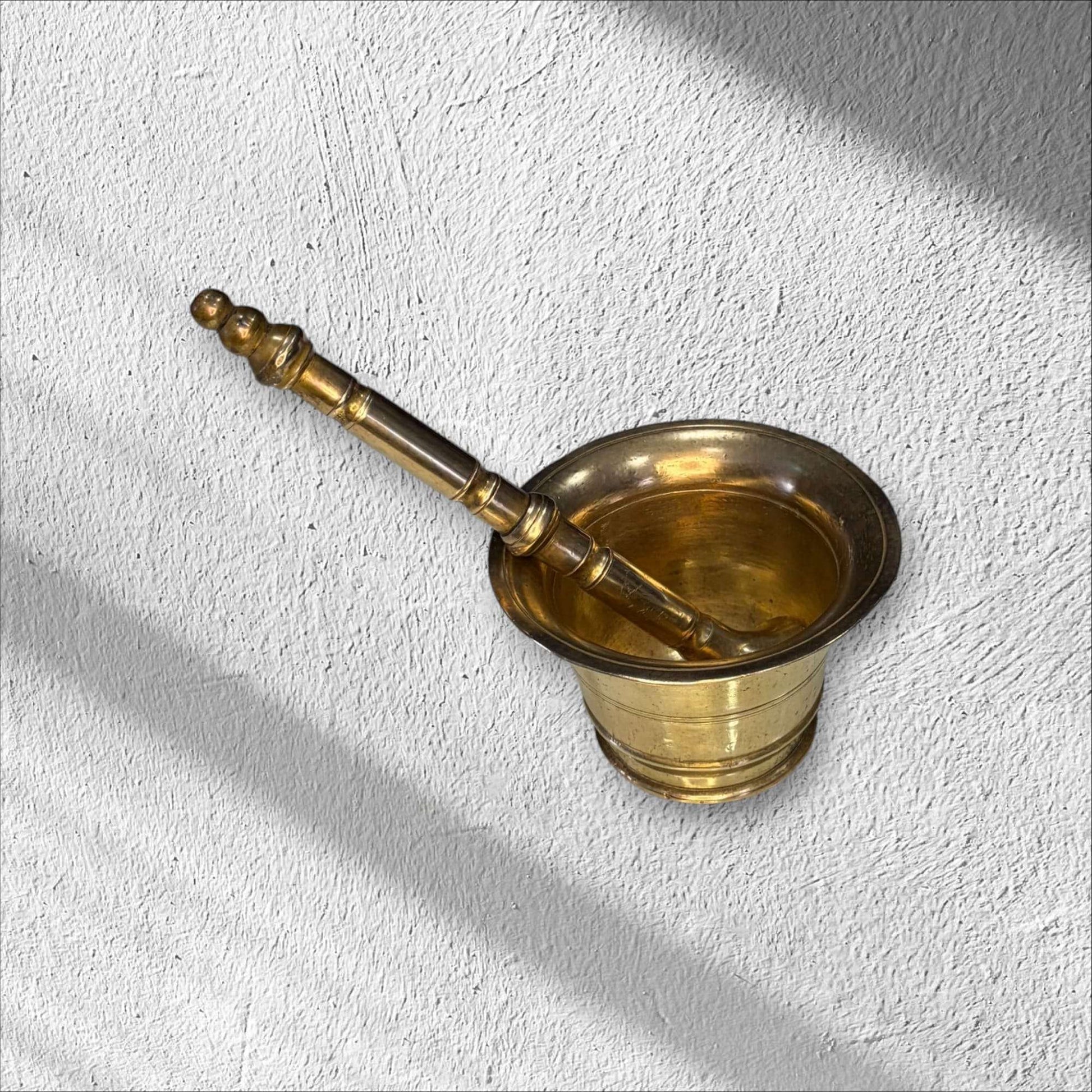 Mortero de bronce antiguo con maja decorativa, pieza rústica ideal para cocina tradicional o decoración vintage en hogar y jardín.