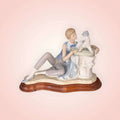 Figura de Niño con perro Nao Lladró en porcelana original, niño recostado acariciando a su perro sobre base de madera, ideal para decoración del hogar.