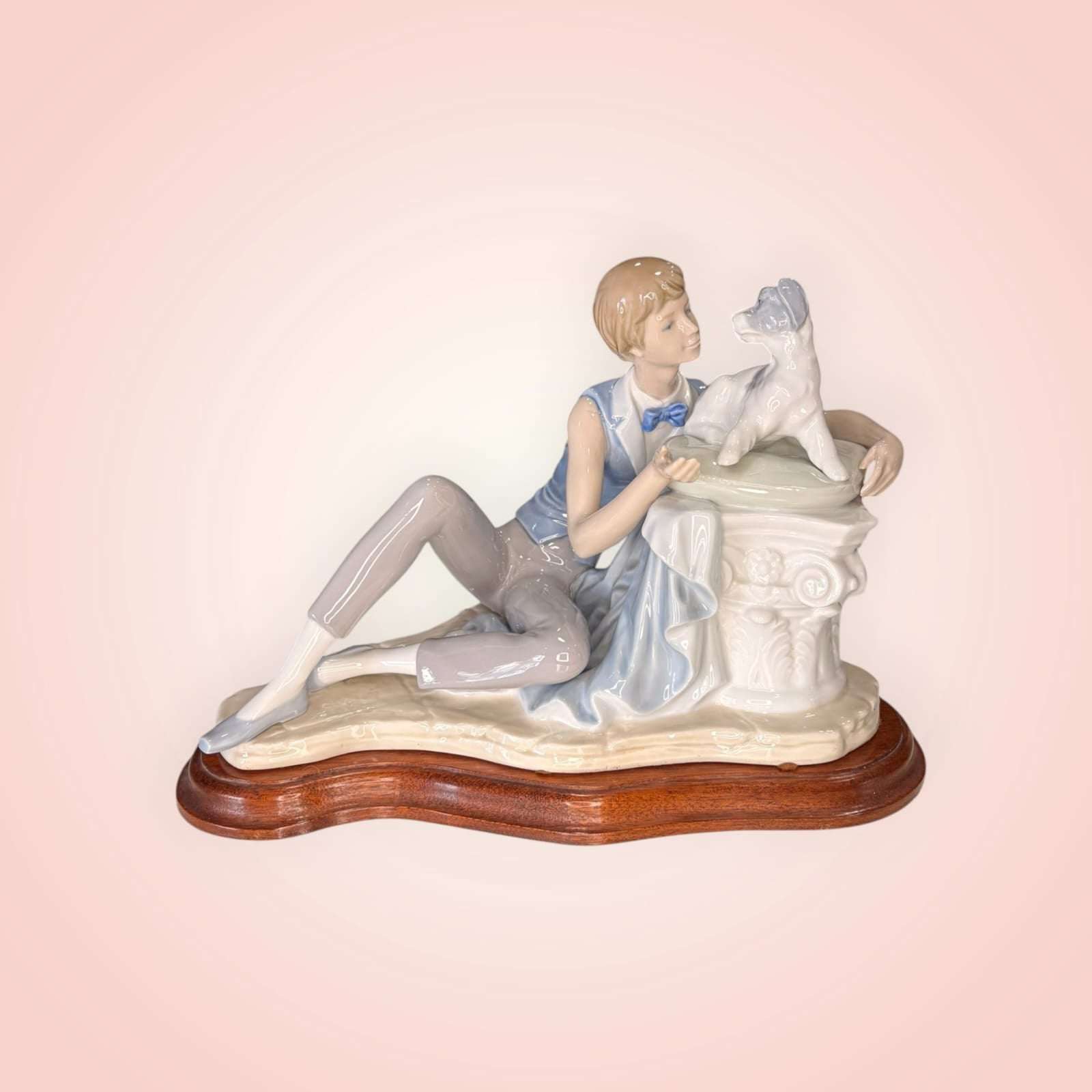 Figura de Niño con perro Nao Lladró en porcelana original, niño recostado acariciando a su perro sobre base de madera, ideal para decoración del hogar.