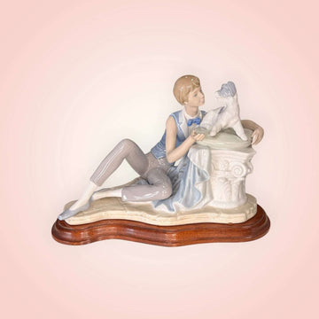 Figura de Niño con perro Nao Lladró en porcelana original, niño recostado acariciando a su perro sobre base de madera, ideal para decoración del hogar.