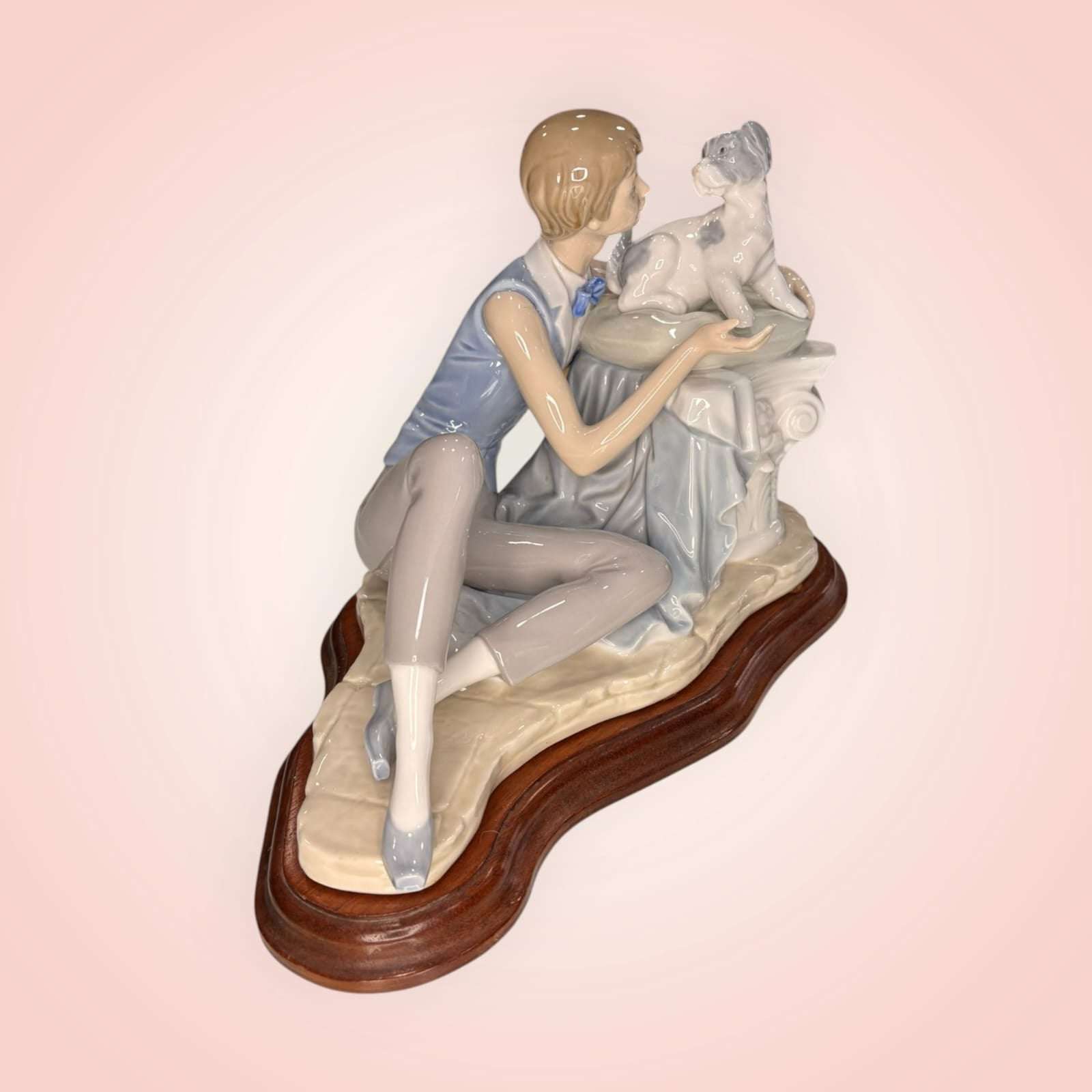 Vista trasera de la figura de Niño con perro Nao Lladró, niño arrodillado frente a su perro sobre pedestal, porcelana decorativa para hogar elegante.