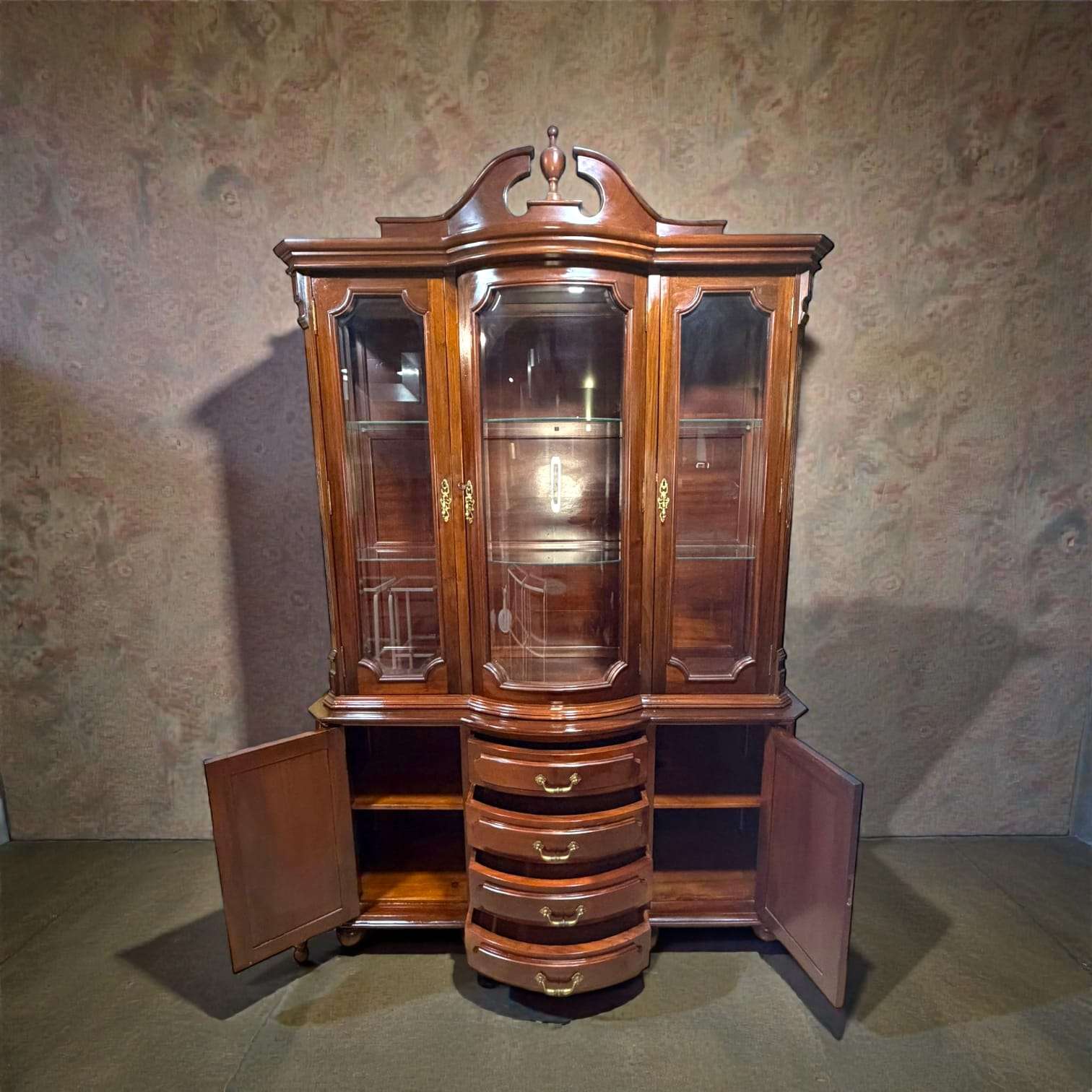 Vitrina de caoba clásica antigua con cristales biselados, tres puertas superiores de vidrio y cajones curvos centrales. Ideal para decoración de salón o comedor.