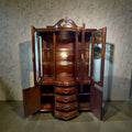 Vitrina de caoba clásica antigua con cristales biselados, puertas abiertas, cajones centrales y estantes de vidrio. Ideal para decoración de salón elegante.