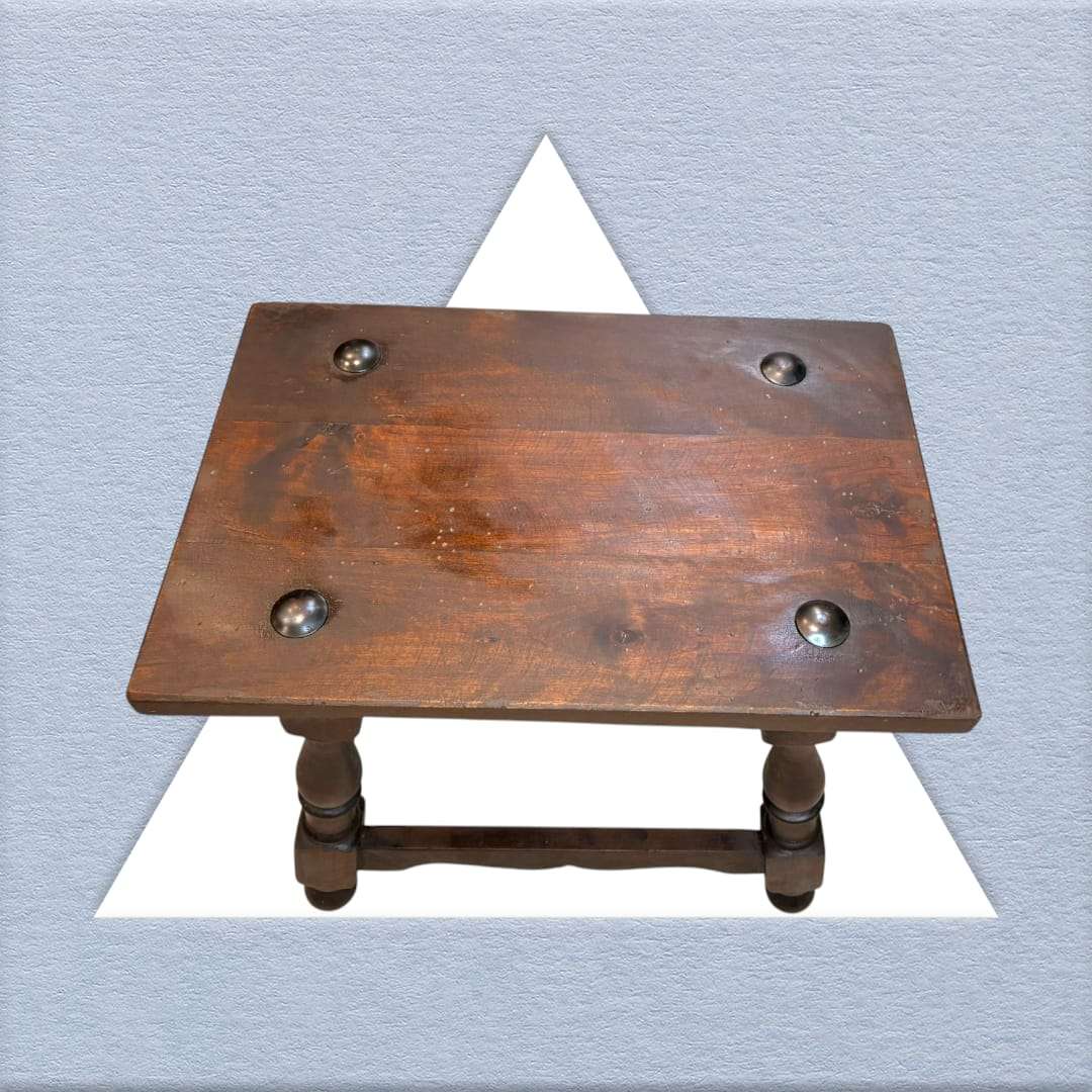 Vista superior de la mesa auxiliar Castellana de madera maciza con remaches metálicos. Pieza decorativa única para el hogar.
