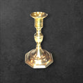 Candelabro de bronce clásico con base octagonal sobre fondo oscuro, ideal para decoración tradicional en interiores elegantes.