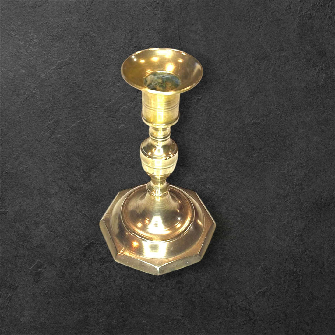 Candelabro de bronce clásico con base octagonal sobre fondo oscuro, ideal para decoración tradicional en interiores elegantes.