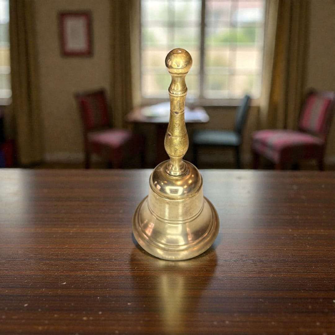 Campana de metal dorado antigua en primer plano sobre superficie de madera. Decoración vintage para hogar con timbre claro y elegante.