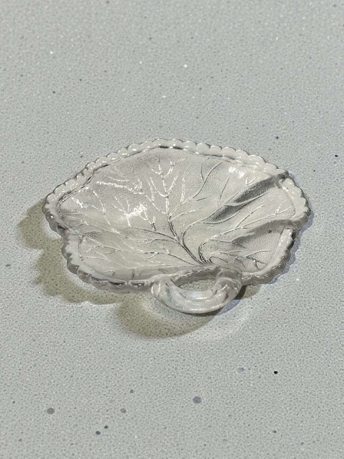 Lote de platos de cristal con forma de hoja antiguos sobre fondo burdeos. Diseño detallado ideal para decoración vintage en el hogar.
