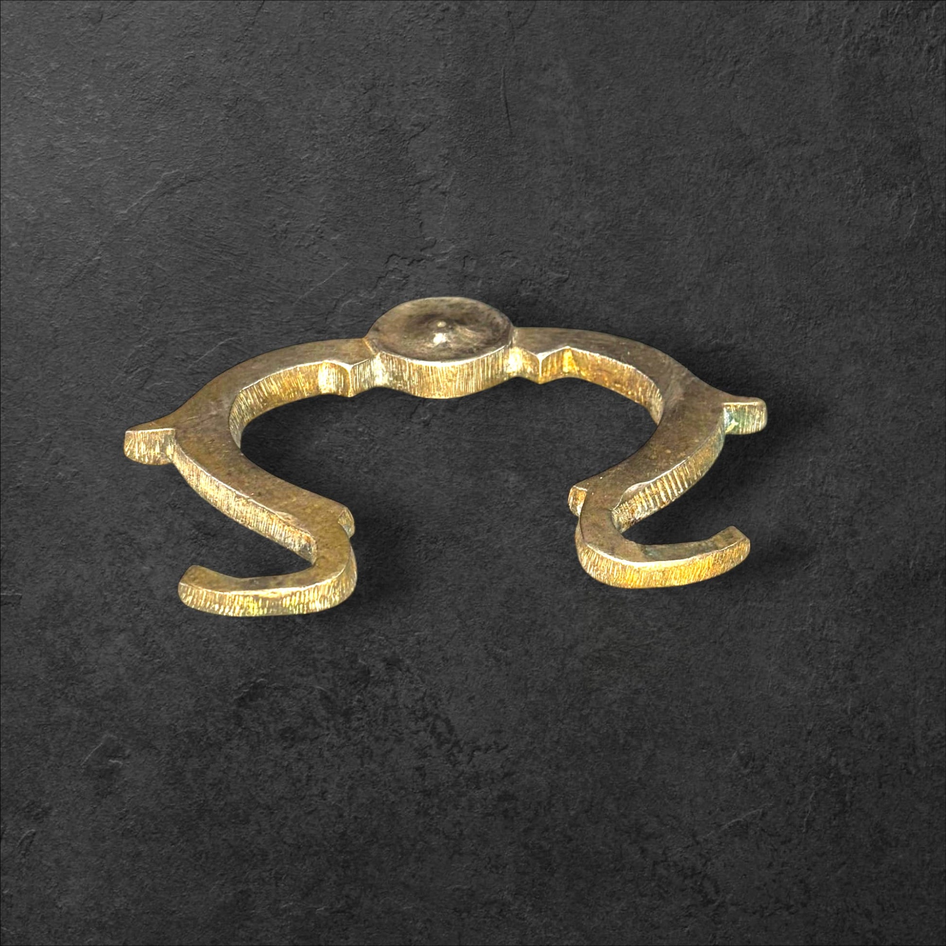 Tirador de metal antiguo original para muebles único con diseño curvo y acabado envejecido sobre fondo oscuro. Ideal para decoración vintage.