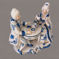 Decoración de porcelana azul y blanca estilo victoriano con pareja sentada en mesa de té, ideal para coleccionistas de figuras vintage.