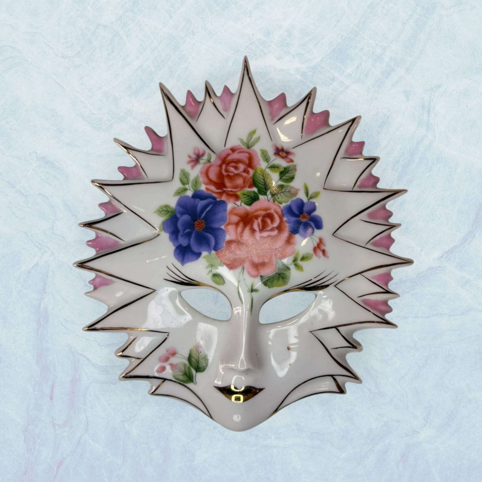 Máscara de porcelana veneciana Galos y Ocer única con diseño floral y bordes puntiagudos, pieza decorativa llamativa para el hogar.