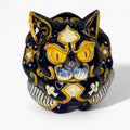 Gato de loza decorativa con detalles en azul, dorado y símbolos de la suerte