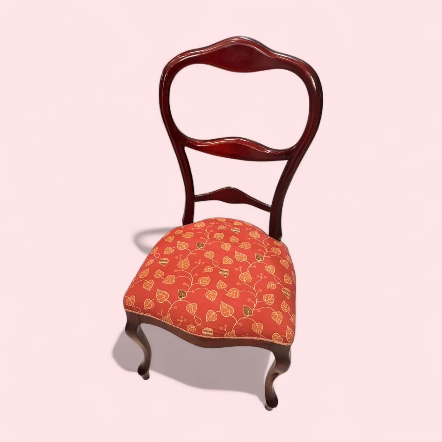 Silla clásica de madera con asiento tapizado floral en tonos rojos y dorados