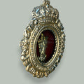  Presenta una estructura de formato ovalado, coronada en la parte superior por una corona en relieve, un detalle de fuerte presencia visual y simbólica. 
