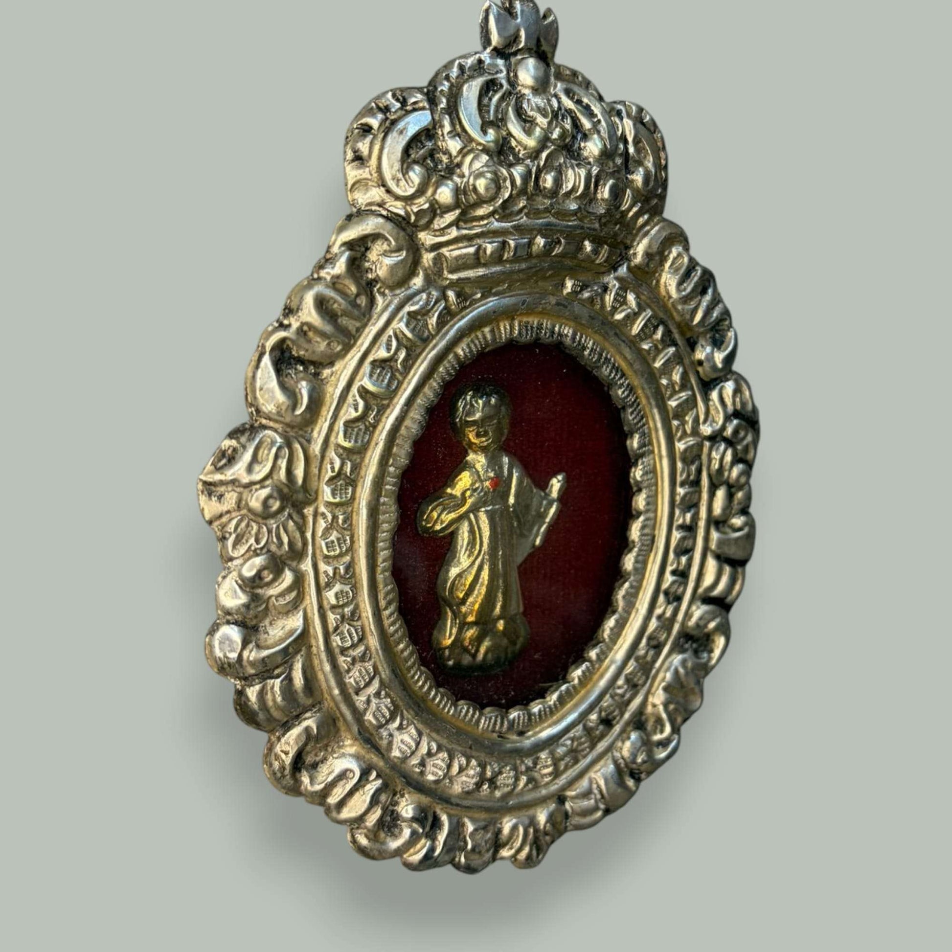 Presenta una estructura de formato ovalado, rematada en la parte superior por una corona en relieve, elemento de fuerte presencia simbólica y visual. 