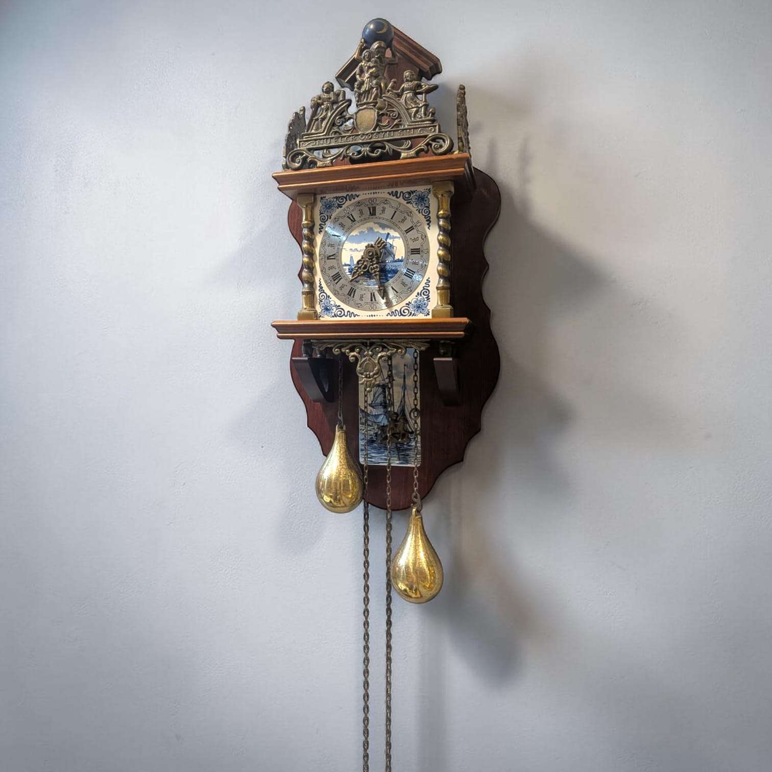 Reloj de pared vintage de madera y metal con peso dorado