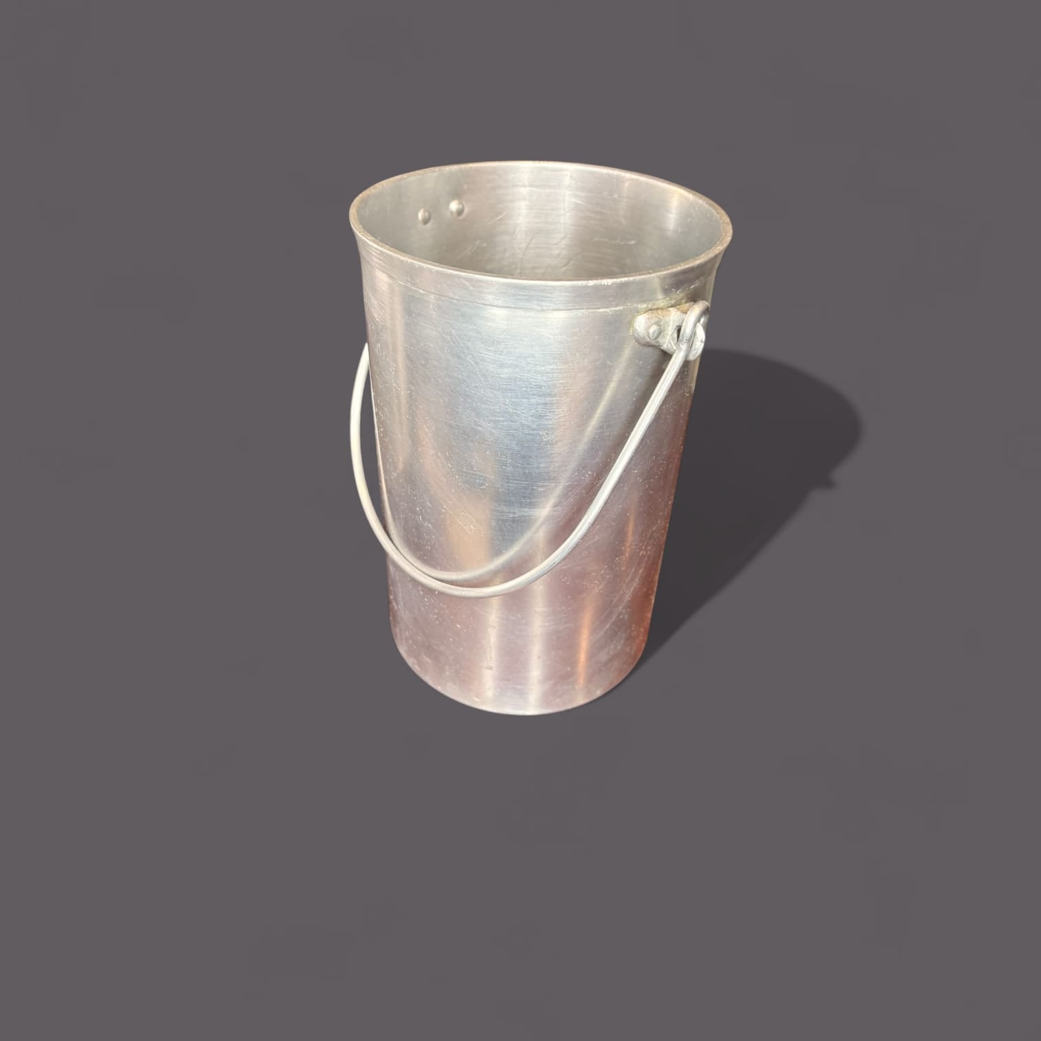 Su superficie muestra acabado en aluminio mate con brillo suave, acompañado de pequeñas marcas, rozaduras y señales de uso que reflejan su historia real. 