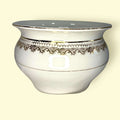 A nivel visual, destaca por su porcelana blanca esmaltada, su asa lateral integrada, su perfil ancho y envolvente y una refinada decoración en tonos dorados.