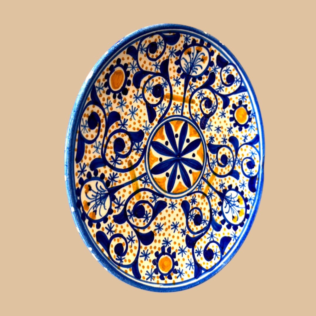En las fotos se aprecia una composición muy cuidada, con motivo floral central, una red de roleos vegetales en azul cobalto, pequeños detalles estrellados y puntos en ocre cálido, todo ello sobre fondo claro.