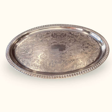 Bandeja antigua de metal plateado con relieves decorativos y borde elevado, pieza vintage para decoración y servicio.