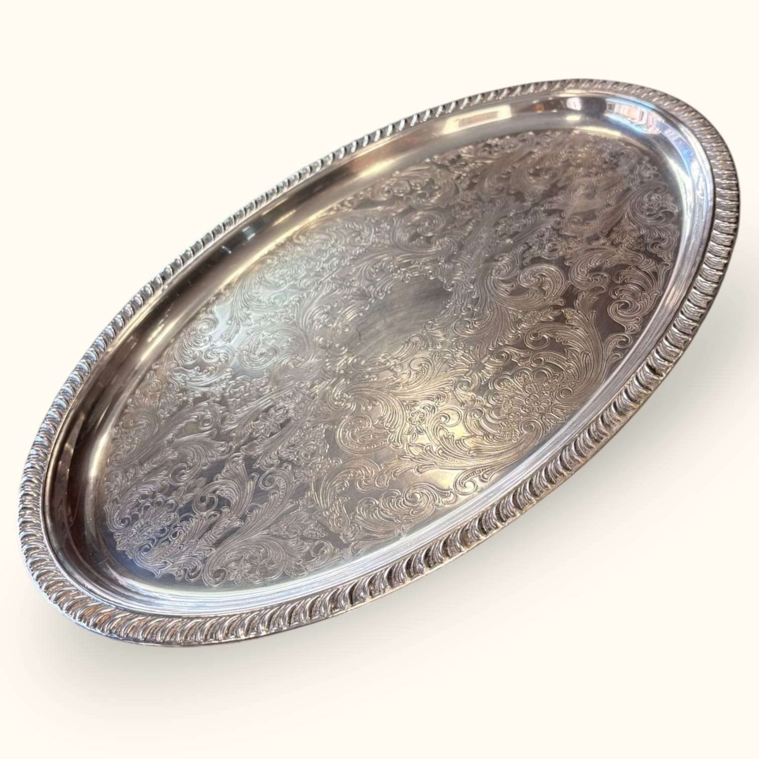 Bandeja antigua de metal plateado con relieves decorativos y borde elevado