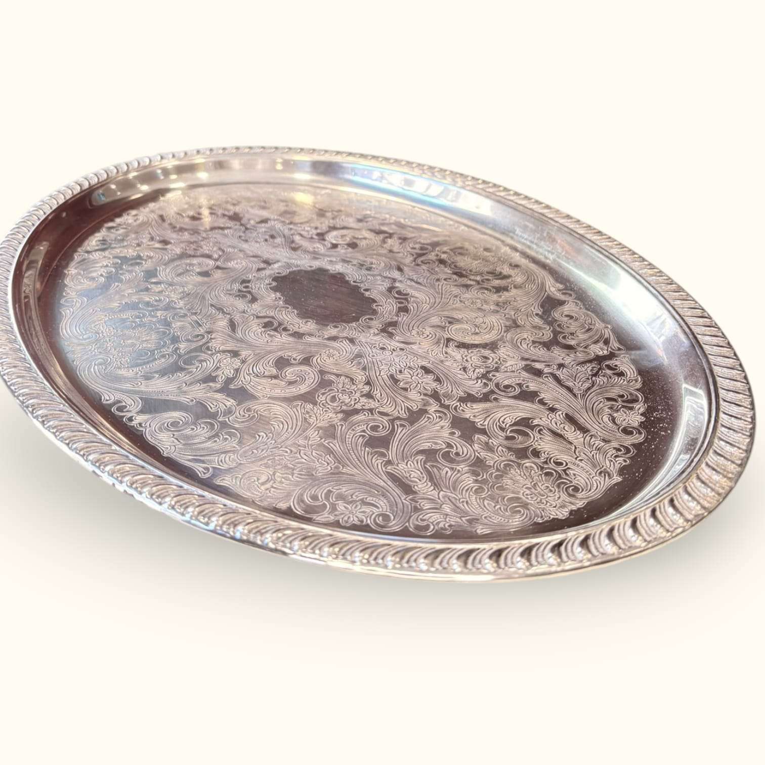 Bandeja antigua de metal plateado con relieves florales y borde elevado