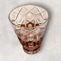 Su diseño combina cristal transparente tallado con franjas cálidas en ámbar, creando un contraste muy decorativo para vitrinas, aparadores, mesas auxiliares o espacios de interiorismo clásico y vintage.